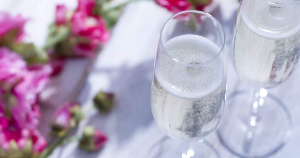Two glasses of champagne and pink flowers on a table