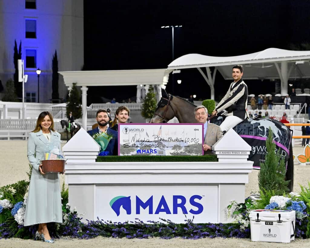 Five people and a horse pose with a large check for $60,000 at an equestrian event. The check is displayed on a white podium with the MARS logo.