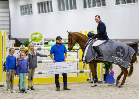 rider and horse pose with fans and check