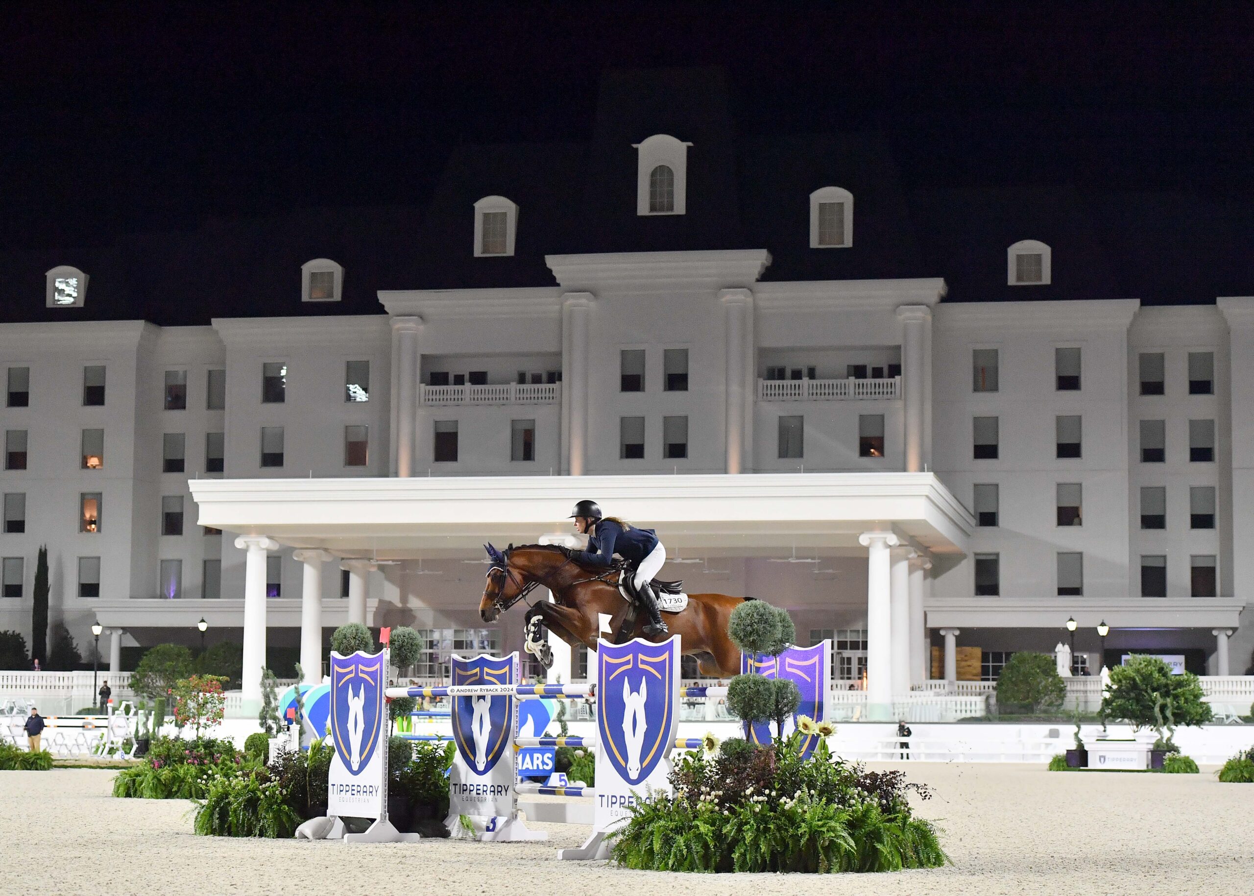 A horse jumping in the Grand Arena at The Equestrian Hotel.