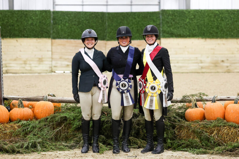 Three award-winning equestrians pose with an autumn display