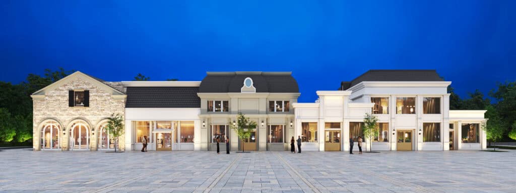 A large, elegant building complex with classical and modern architectural elements, illuminated at night with people standing in front on a wide stone plaza.