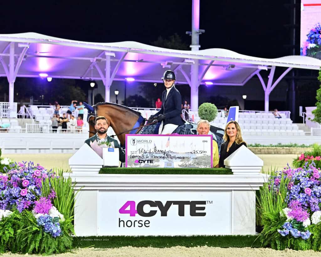 Four people and a horse pose with a large check on a decorated podium at an equestrian event sponsored by 4CYTE Horse, with empty seats in the background.