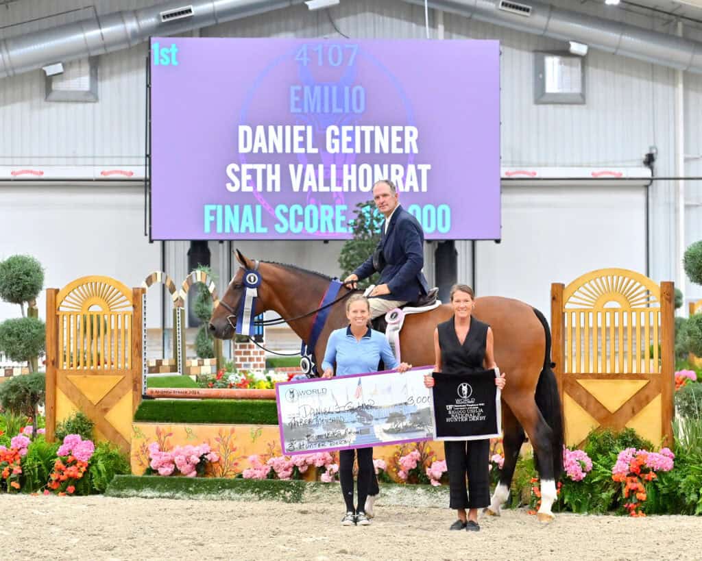 A man on a horse poses with two women holding a large check. A display behind them shows "Daniel Geitner, Seth Vallhonrat, Final Score: 8900." The arena is decorated with flowers.