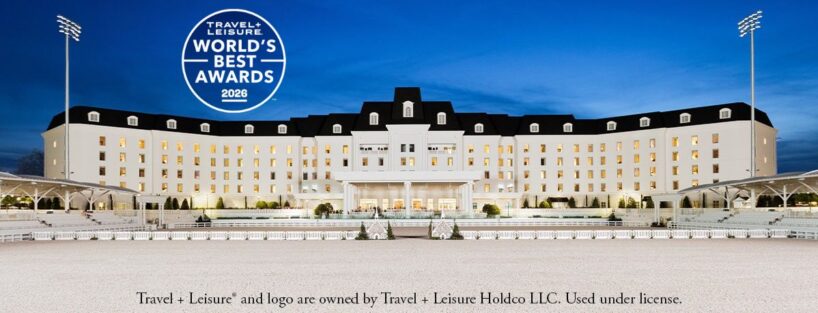 A large, elegant hotel with white exterior and black roof is lit up at dusk, with "Travel + Leisure World's Best Awards 2026" logo in the sky above it.