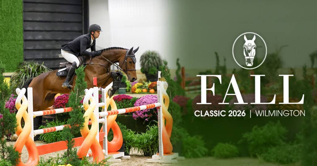 A rider on a horse jumps over an obstacle at an indoor equestrian event; text reads "Fall Classic 2026 Wilmington.