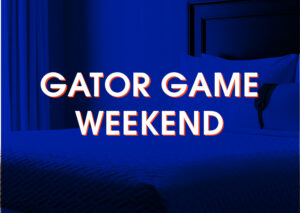A neatly made bed in a hotel room with the words “Gator Game Weekend” overlaid in bold white text.