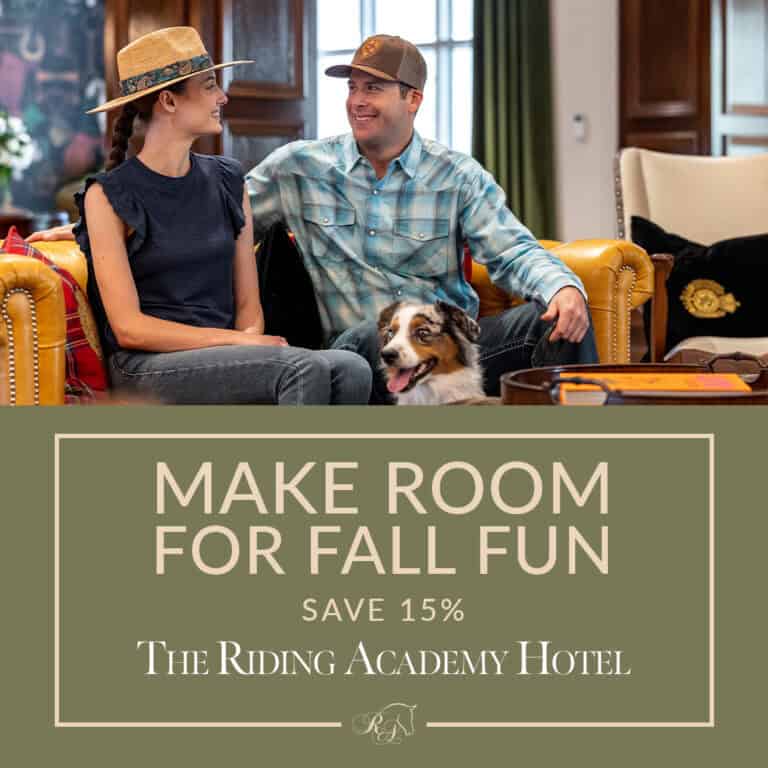 A woman and man sit on a yellow couch with a dog indoors. Text below reads: “Make Room For Fall Fun. Save 15%. The Riding Academy Hotel.”.