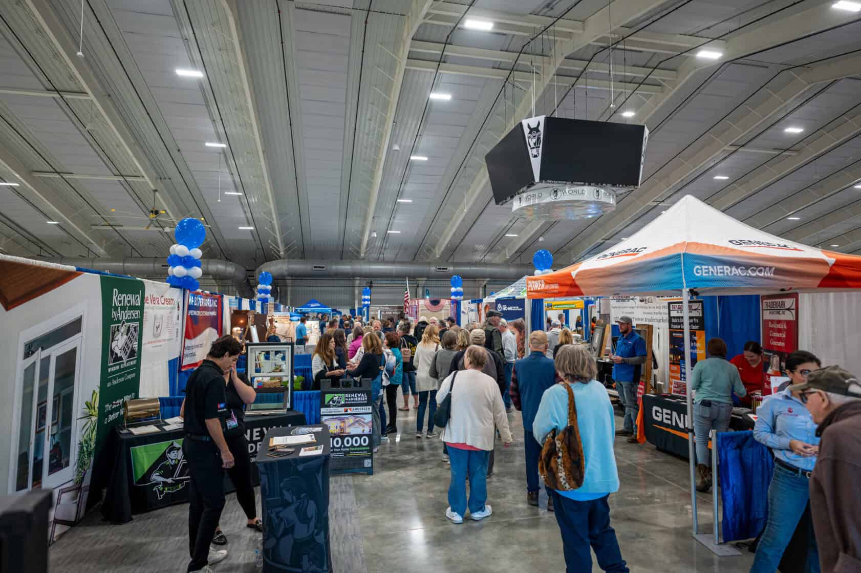 People walk through an indoor trade show with vendor booths, informational displays, and banners under a high arched ceiling.