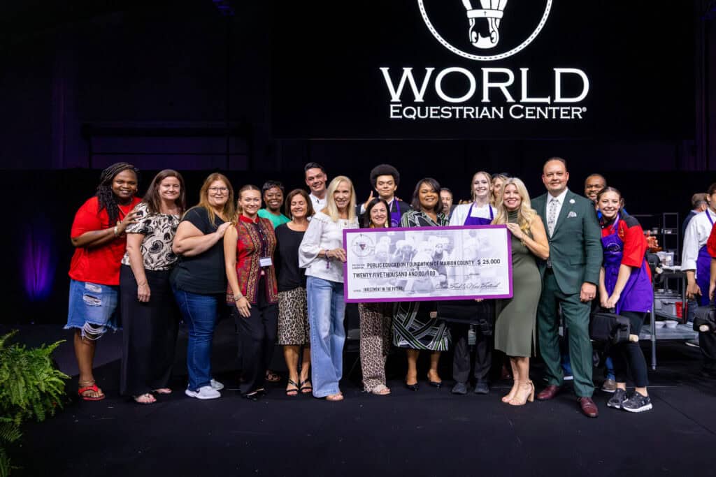 A large group of people standing on a stage holding a ceremonial check for $25,000 for the Public Education Foundation of Marion County.