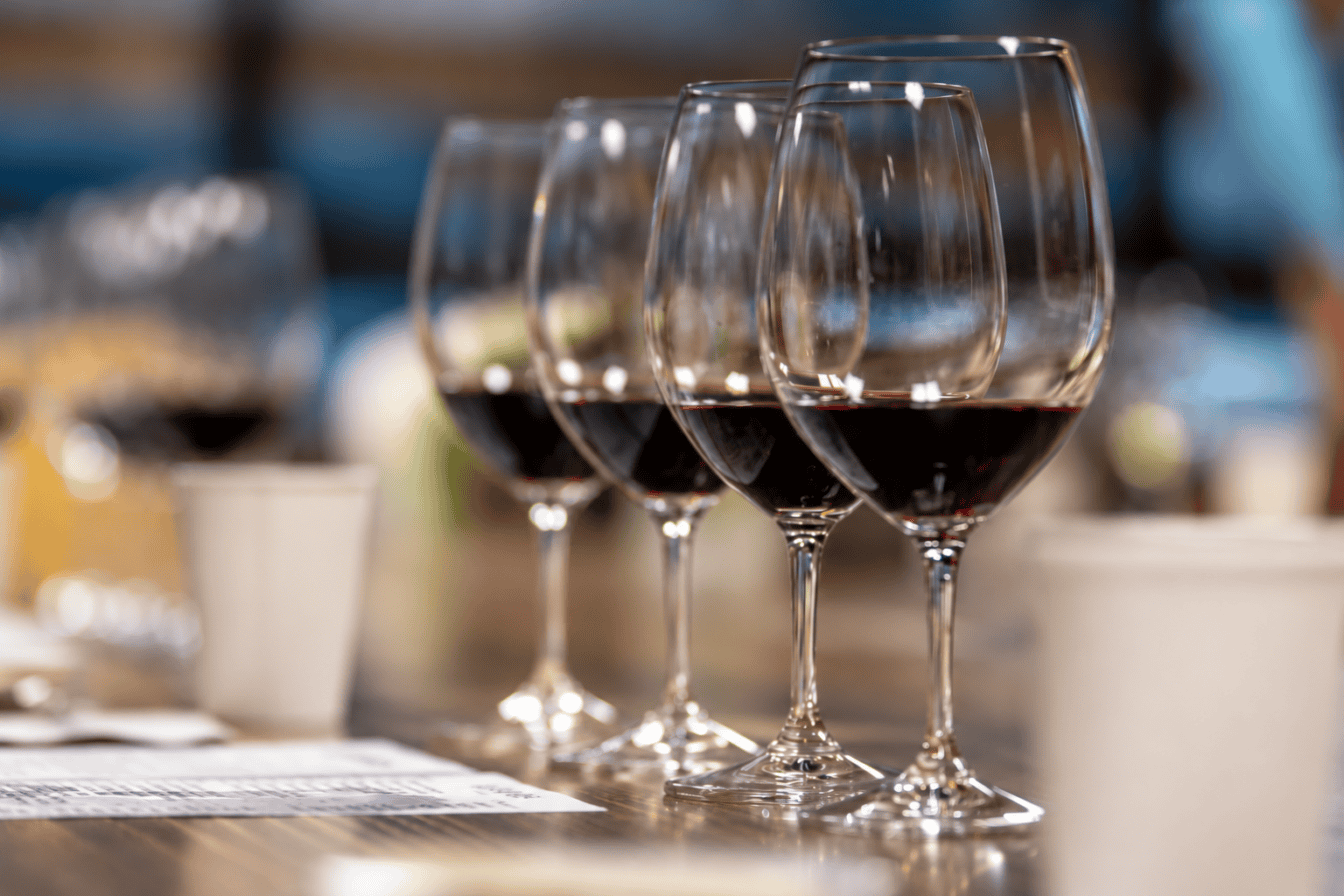 A row of wine glasses filled with red wine on a table.